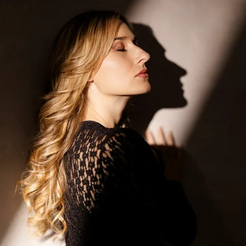 Portrait d'une femme blonde en robe noire, &eacute;clair&eacute;e par un rayon de lumi&egrave;re par le photographe &agrave; Grenoble