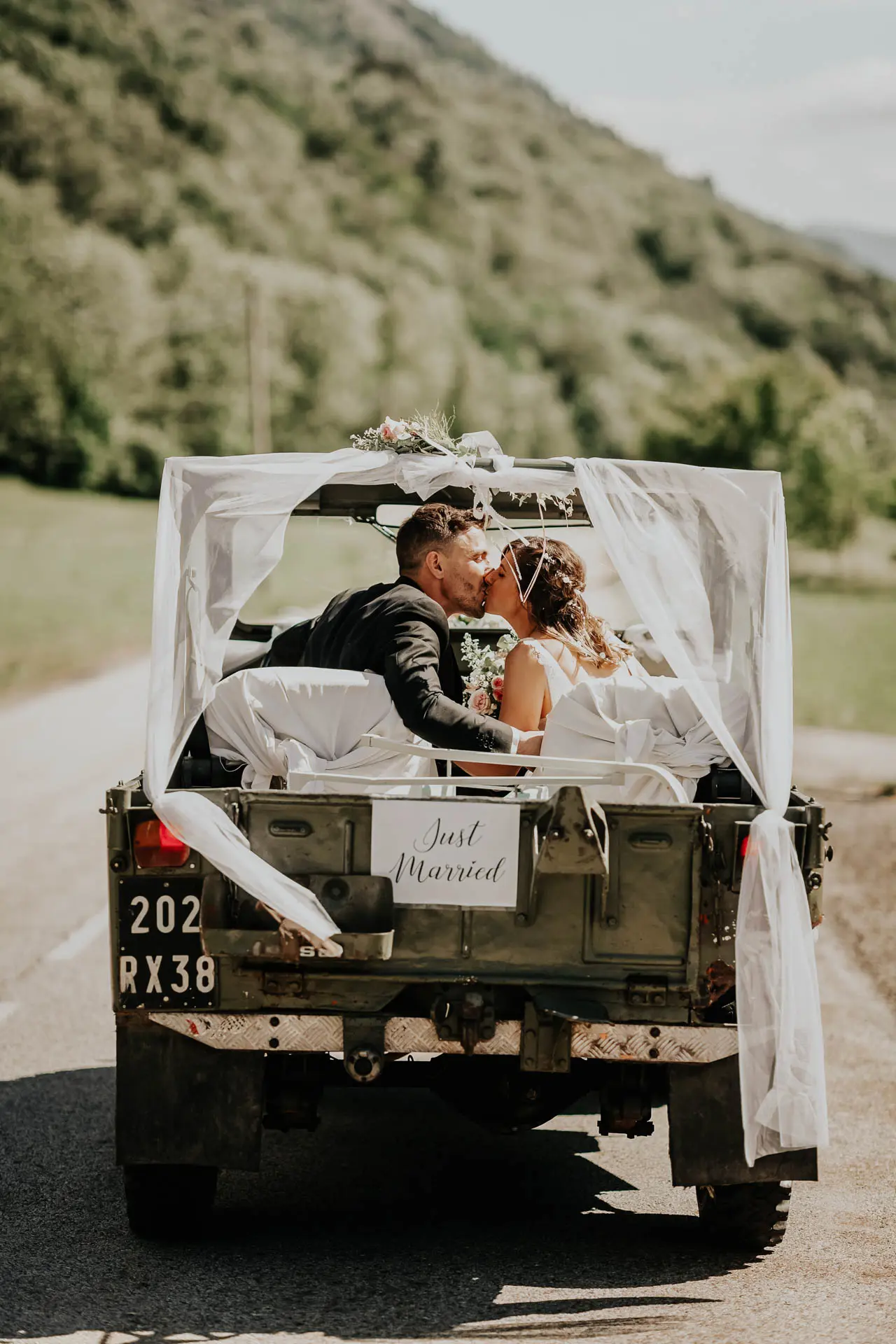 photo d'un couple de mariés de dos, s'embrassant dans la voiture