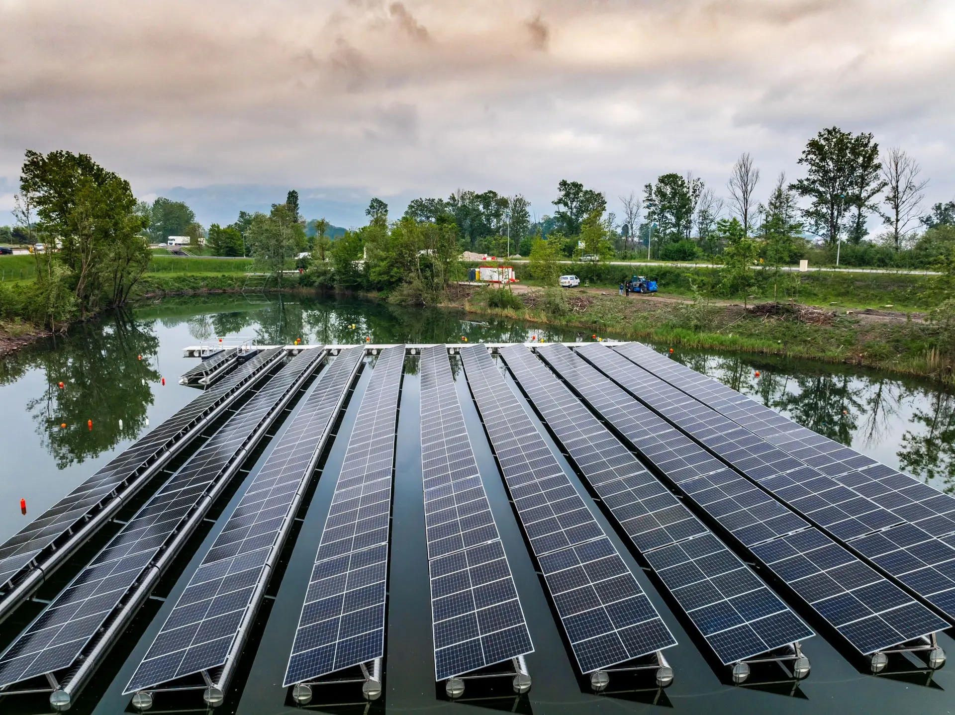 Rangées de panneaux solaires flottants en enfilade sur un lac, sous un ciel couvert