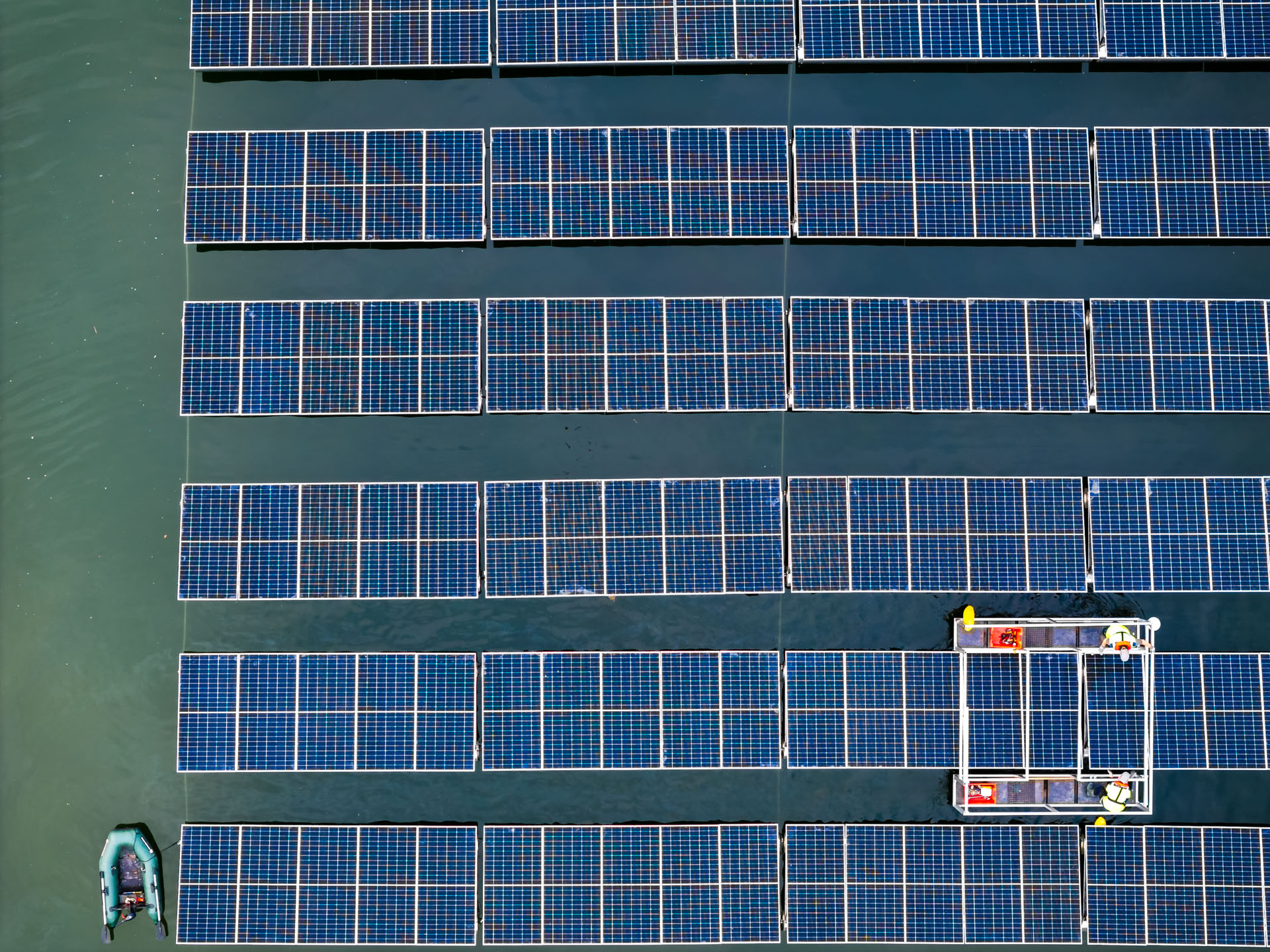 Vue zénithale de panneaux photovoltaïques flottants avec deux techniciens sur une plateforme